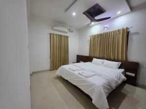 a bedroom with a bed with white sheets and a ceiling at Ixe Stays in Mangalore