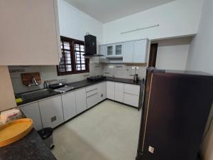 a kitchen with white cabinets and a black counter top at Ixe Stays in Mangalore