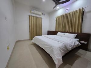 a bedroom with a large bed with white sheets at Ixe Stays in Mangalore +5 photos