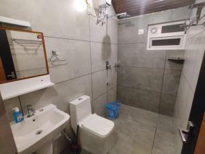 ein Badezimmer mit Toilette, Waschbecken und Spiegel in der Unterkunft The Vagabond Stays in Vagamon + 26 Fotos