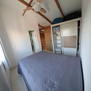 a bedroom with a blue bed and a ceiling fan at Mini Casa Mezanino in São Francisco do Sul