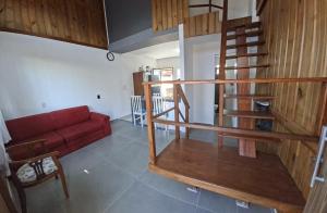 a living room with a red couch and a spiral staircase at Mini Casa Mezanino in São Francisco do Sul +4 photos