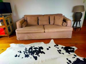 ein Wohnzimmer mit einem Sofa und einem Kuhteppich in der Unterkunft Ferienwohnung "Hochfeld Seeblick" in Tegernsee