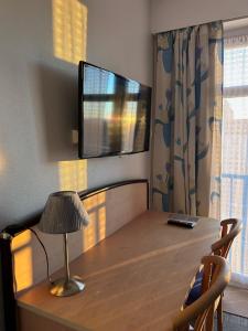 een woonkamer met een tafel en een televisie aan de muur bij Hotel le France, Redon in La Celle-sous-Gouzon