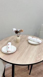 een houten tafel met twee borden en een vaas met bloemen bij Angel apart in Astana +3 foto's