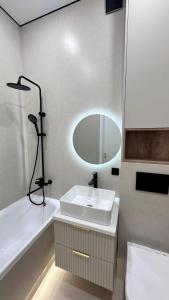 een badkamer met een wastafel, een bad en een spiegel bij Angel apart in Astana