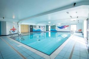 a large swimming pool with two chairs in a building at Casa MALC Caravan in Lossiemouth