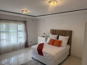 a bedroom with a bed with orange pillows on it at Borrowdale Top End - Apartments in Harare