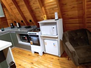 a kitchen with a stove and a refrigerator and a chair at Cabana Encanto da Mata in Santa Maria do Erval