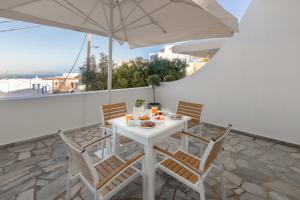a white table with chairs and an umbrella on a balcony at Nevma Suites in Firostefani