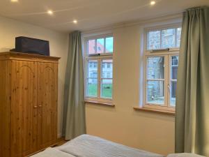- une chambre dotée de fenêtres, d'un lit et d'une télévision dans l'établissement Altstadt Apartment, à Pattensen