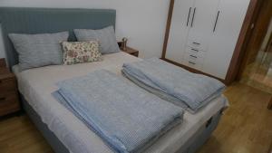 a bed with blue sheets and pillows on it at Apartmani Flocke Vlašić in Šišava