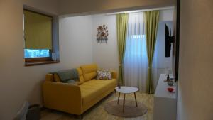 a living room with a yellow couch and a table at Apartmani Flocke Vlašić in Šišava