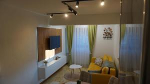 a living room with a yellow couch and a tv at Apartmani Flocke Vlašić in Šišava