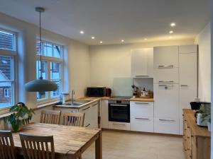 a kitchen with white cabinets and a wooden table at Altstadt Apartment in Pattensen