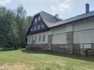 a large stone building with a black roof at Chalupa Bartlův Dvůr in Bartošovice v Orlických Horách