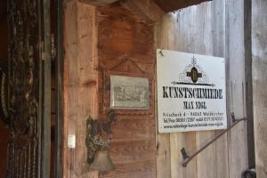a sign on a wooden wall with a bell at Pension Aigner in Waldkirchen