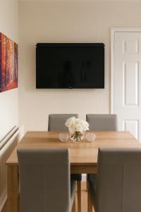 a dining room table with chairs and a television on the wall at Comfortable Two Bedroom Home in Cwm-brân