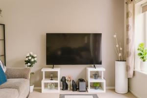 a living room with a large flat screen tv on a wall at Comfortable Two Bedroom Home in Cwm-brân +8 photos