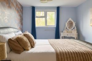 a bedroom with a bed with blue walls and a window at Comfortable Two Bedroom Home in Cwm-brân