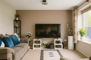 a living room with a couch and a flat screen tv at Comfortable Two Bedroom Home in Cwm-brân