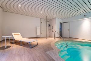 a pool in a room with a chair and a table at NEU! HeideVilla - Private Pool, Sauna & Mini Golf in Asendorf