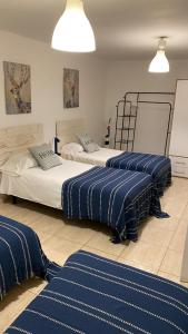three beds in a room with blue and white sheets at Alojamiento Temporal Corazón Madrid in Madrid