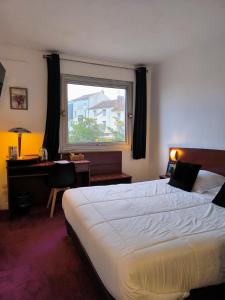 a bedroom with a bed and a desk and a window at Hôtel Saint Jacques in Parthenay