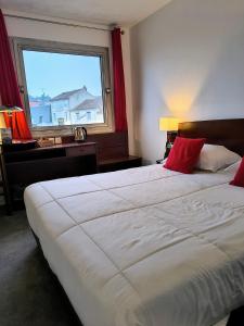 two beds in a hotel room with a window at Hôtel Saint Jacques in Parthenay +121 photos