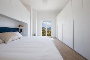 a white bedroom with a large bed and a window at Villa Carpediem - Luxury Private Stay Front Sea Portofino Coast in Recco