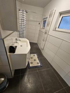 een witte badkamer met een wastafel en een raam bij Ferienhaus Neunkirchen-Daun in Daun