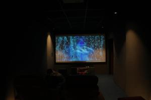 a person sitting in front of a large screen television at Apna Ghar in Jaipur