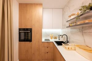 kuchnia z białymi szafkami i czarną kuchenką mikrofalową w obiekcie Apartman G1 w mieście Pale