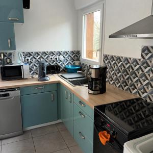 La cuisine est équipée de placards bleus et d'un four avec plaques de cuisson. dans l'établissement Loc de Thies, à Grayan-et-lʼHôpital