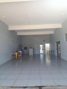 an empty room with a white tile floor and a kitchen at Área de lazer in Assis
