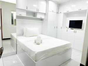 a white room with a bed and a tv at Valhali Guesthouse in Huraa