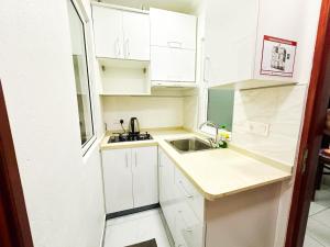 a small kitchen with white cabinets and a sink at Valhali Guesthouse in Huraa