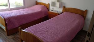 two beds in a room with purple sheets at Complejo Aires del Cielo in San José