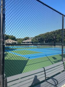 a tennis court seen through a fence with a bench at Blue Skies Seaside Veranda in New Smyrna Beach
