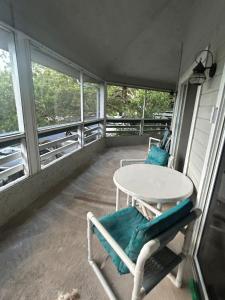 a balcony with a table and chairs and windows at Blue Skies Seaside Veranda in New Smyrna Beach