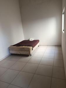 a bed in a white room with a tiled floor at Área de lazer in Assis