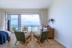 ein Schlafzimmer mit Tisch und Stühlen mit Blick auf das Meer in der Unterkunft Dune Beach House in Wilderness