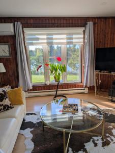ein Wohnzimmer mit einem Glastisch vor einem Fenster in der Unterkunft La Maison Kelner in Saint Ludger de Milot