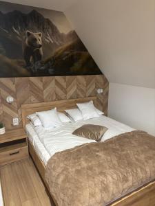een slaapkamer met een groot bed en een schilderij van een beer bij Rusiński Raj - Domki in Bukowina Tatrzańska