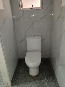een wit toilet in een badkamer met een raam bij Protea Place Cottage in La Mercy