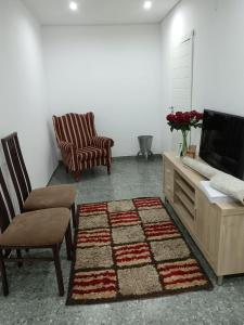 een woonkamer met een tv en 2 stoelen en een tapijt bij Protea Place Cottage in La Mercy