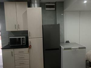 a small kitchen with a refrigerator and a microwave at Protea Place Cottage in La Mercy +2 photos