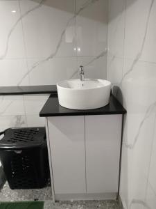 een witte badkamer met een wastafel en een fornuis bij Protea Place Cottage in La Mercy