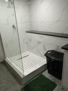a bathroom with a shower and a trash can at Protea Place Cottage in La Mercy