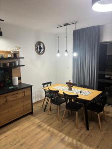 een eettafel met stoelen en een klok aan de muur bij Rusiński Raj - Domki in Bukowina Tatrzańska